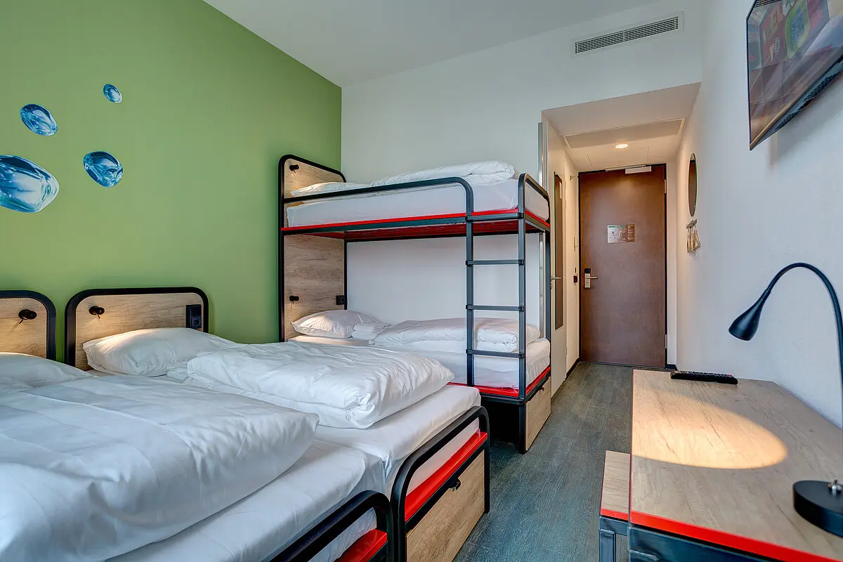 Plain bedroom with two beds, a desk and a window onto a quay