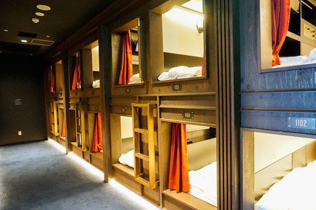 Two tiers of moulded sleeping berths with panelled screens along a corridor